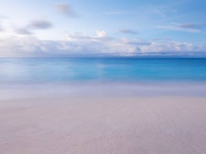 Pristine sandy beach with turquoise water and blue sky with white clouds
